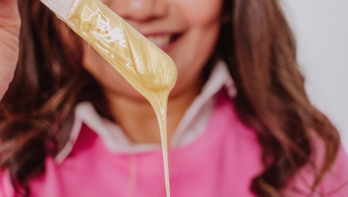 Warm wax drips from a spatula at Edna Neres in Vila Nova De Gaia, Porto, PT, showcasing professional beauty services.