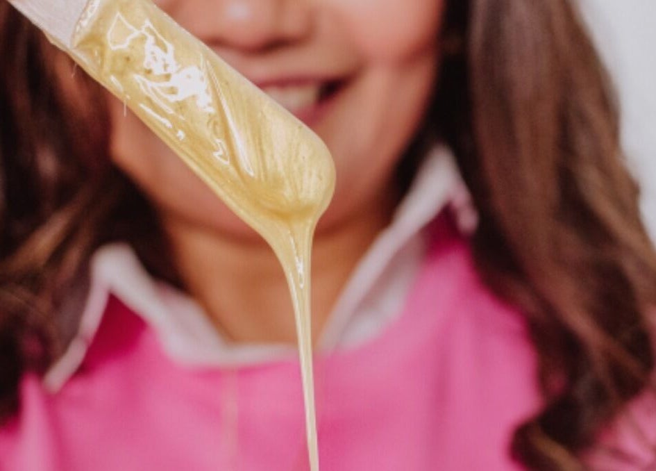 Warm wax drips from a spatula at Edna Neres in Vila Nova De Gaia, Porto, PT, showcasing professional beauty services.