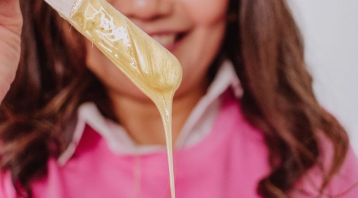 Warm wax drips from a spatula at Edna Neres in Vila Nova De Gaia, Porto, PT, showcasing professional beauty services.