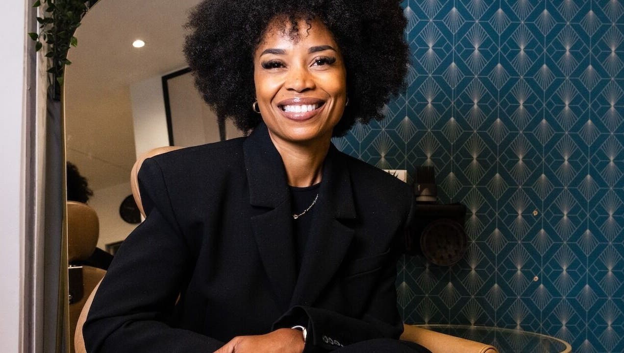Femme souriante à Studio - Rue Clauzel, Paris, Île-de-France, FR, devant une décoration murale élégante.