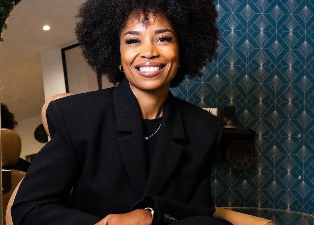 Femme souriante à Studio - Rue Clauzel, Paris, Île-de-France, FR, devant une décoration murale élégante.