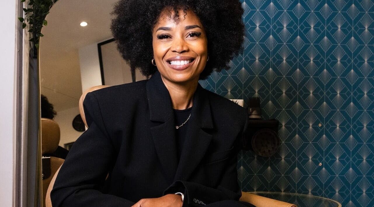 Femme souriante à Studio - Rue Clauzel, Paris, Île-de-France, FR, devant une décoration murale élégante.