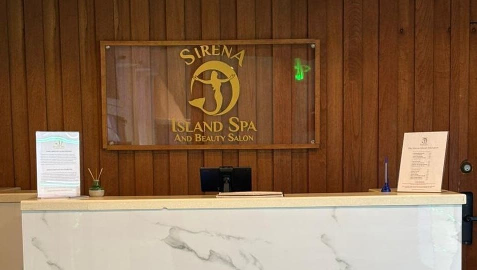 Reception desk at Sirena Island Spa in Noord, Oranjestad, AW, with elegant wooden decor and signage.