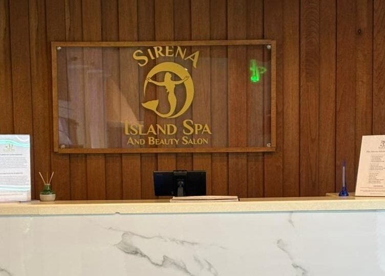 Reception desk at Sirena Island Spa in Noord, Oranjestad, AW, with elegant wooden decor and signage.