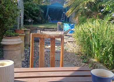 Tranquil garden view at MaxRelax Massage Therapy, London, England, GB, with a wooden chair and lush plants.