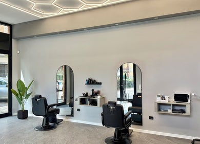 Interno di Barber d’Èlite, Firenze, Toscana, IT, con sedie da barbiere e design elegante.