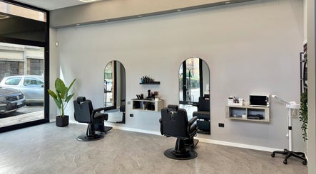 Interno moderno di Barber d'Èlite a Firenze, Toscana, IT con sedie da barbiere e specchi eleganti.