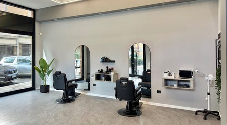 Interno moderno del Barber d’Èlite a Firenze, Toscana, IT, con poltrone eleganti e grandi specchi.