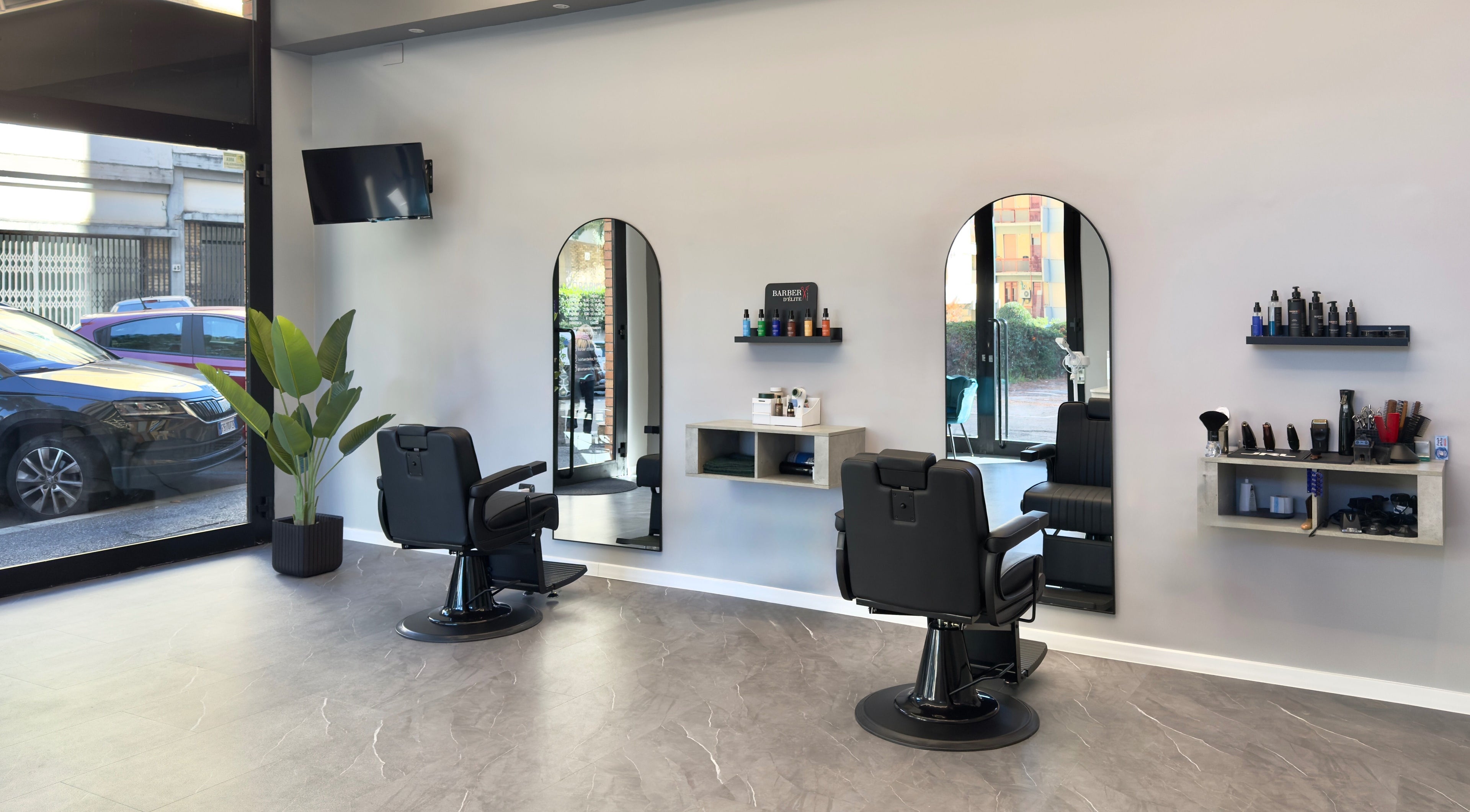 Interno moderno di Barber d’Èlite a Firenze, Toscana, IT con sedie confortevoli e decorazioni chic.