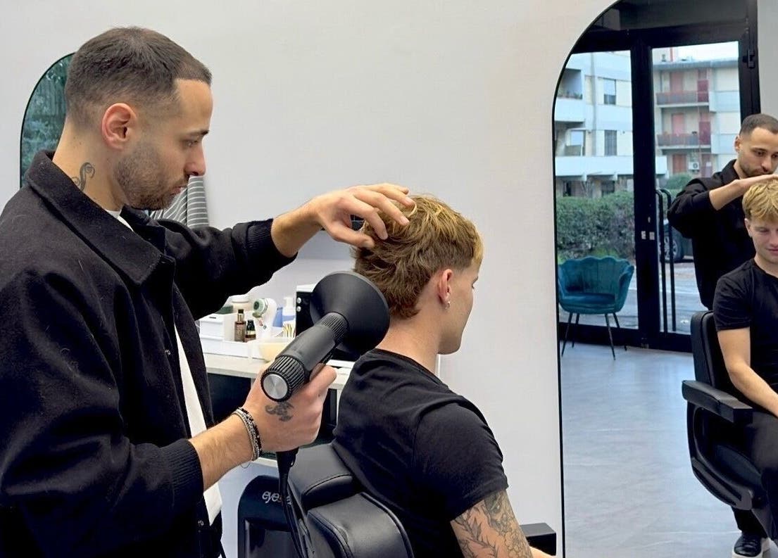Parrucchiere professionale a Barber d’Èlite, Firenze, Toscana, IT, mentre sistema i capelli di un cliente.