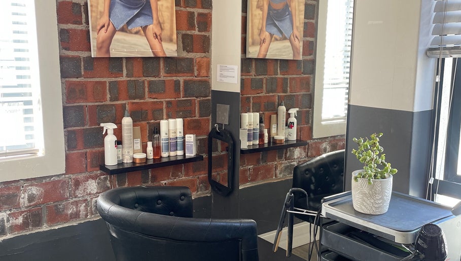 Modern salon interior at Hair by Tess, Cape Town, Western Cape, ZA with chairs, products, and brick wall.