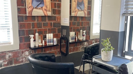Modern salon interior at Hair by Tess, Cape Town, Western Cape, ZA with chairs, products, and brick wall.