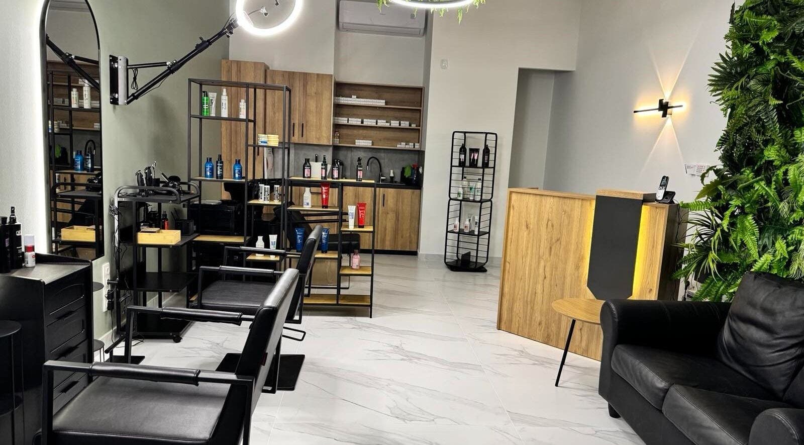 Άνετο σαλόνι στο Gspot Hair Studio, Ilioupoli, GR με μοντέρνα επίπλωση και προϊόντα ομορφιάς.