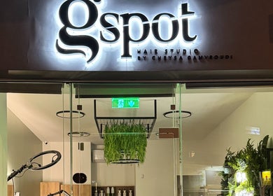 Η εντυπωσιακή είσοδος του Gspot Hair Studio στην Ηλιούπολη, GR με φωτεινό λογότυπο.