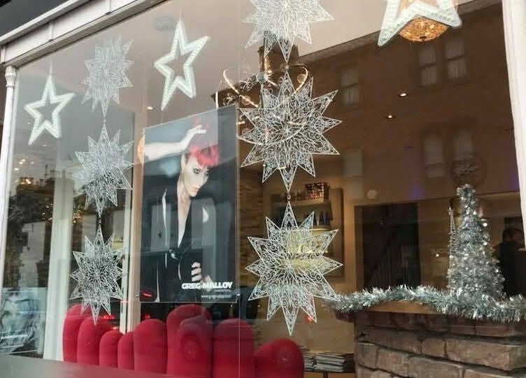 Festive window display at Greg Malloy Hairdressing, Penrith, England with stars and decorations.