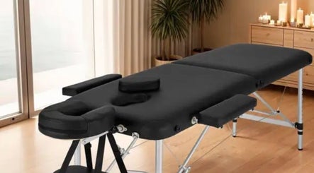 Relaxing therapy room with massage table at Fleming Sports Therapy, GB. Soft lighting and candles create a calm ambiance.