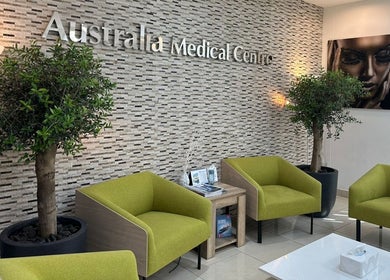 Relaxing waiting area of Australia Medical Centre in Dubai, AE with green chairs and art decor.