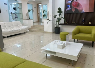 Modern seating area at Australia Medical Centre, Dubai, AE, with green chairs and white sofa.