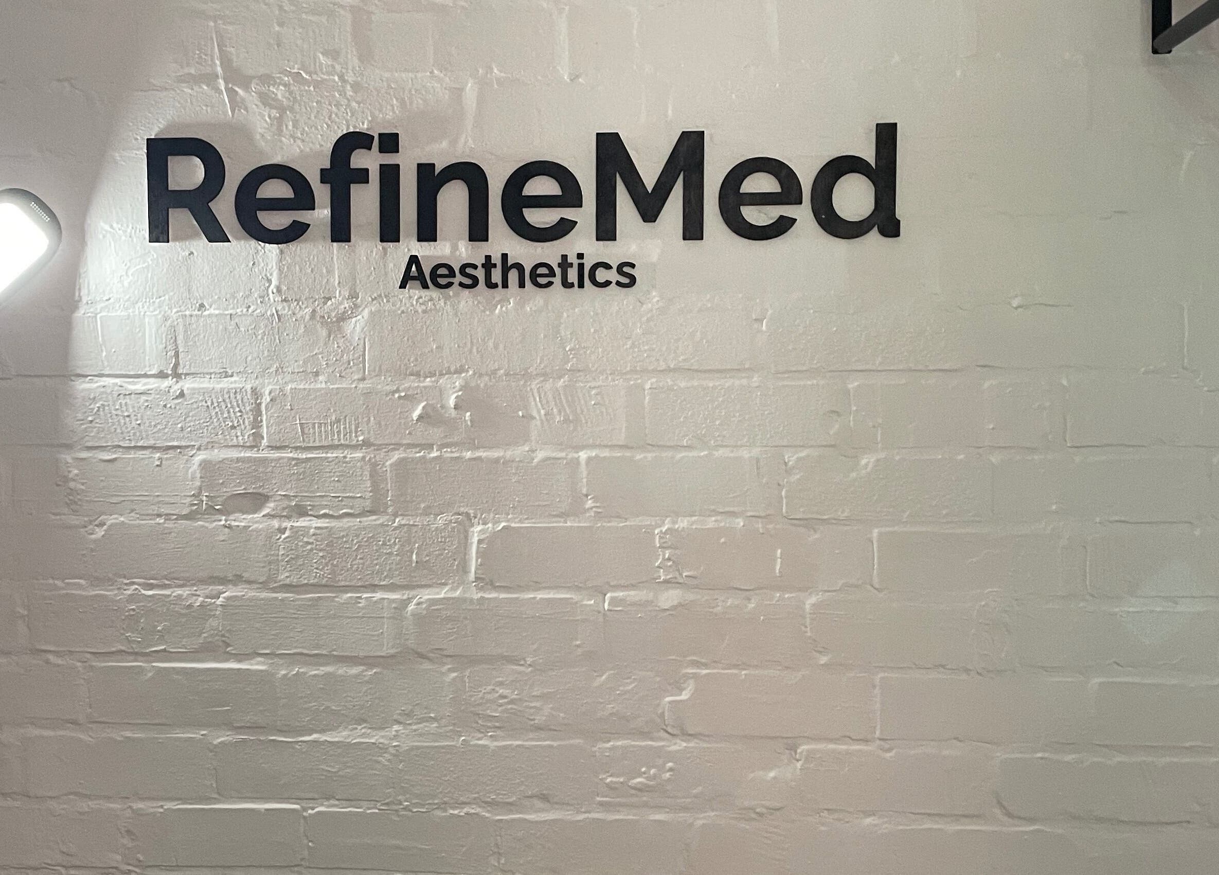 RefineMed Aesthetics sign on brick wall, Newcastle upon Tyne, England, GB, under soft lamp lighting.