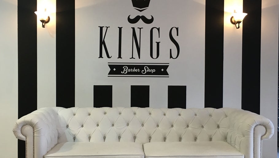 Interior de Kings Barber Shop en Quito, Pichincha, EC, con sofá blanco y diseño elegante en las paredes.