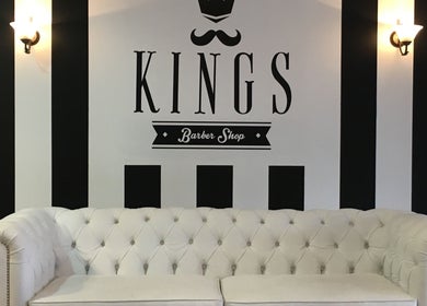 Interior de Kings Barber Shop en Quito, Pichincha, EC, con sofá blanco y diseño elegante en las paredes.