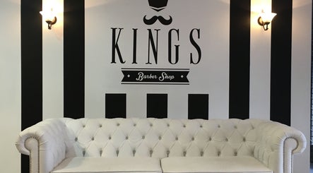Interior de Kings Barber Shop en Quito, Pichincha, EC, con sofá blanco y diseño elegante en las paredes.