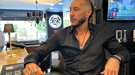 Interior de Kings Barber Shop, Quito, Pichincha, EC, con un hombre elegante en el mostrador.