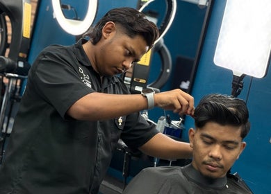 Barber expertly cuts hair at Daqiq Barbershop in Simpang Empat, Kedah, MY, showcasing precision and style.