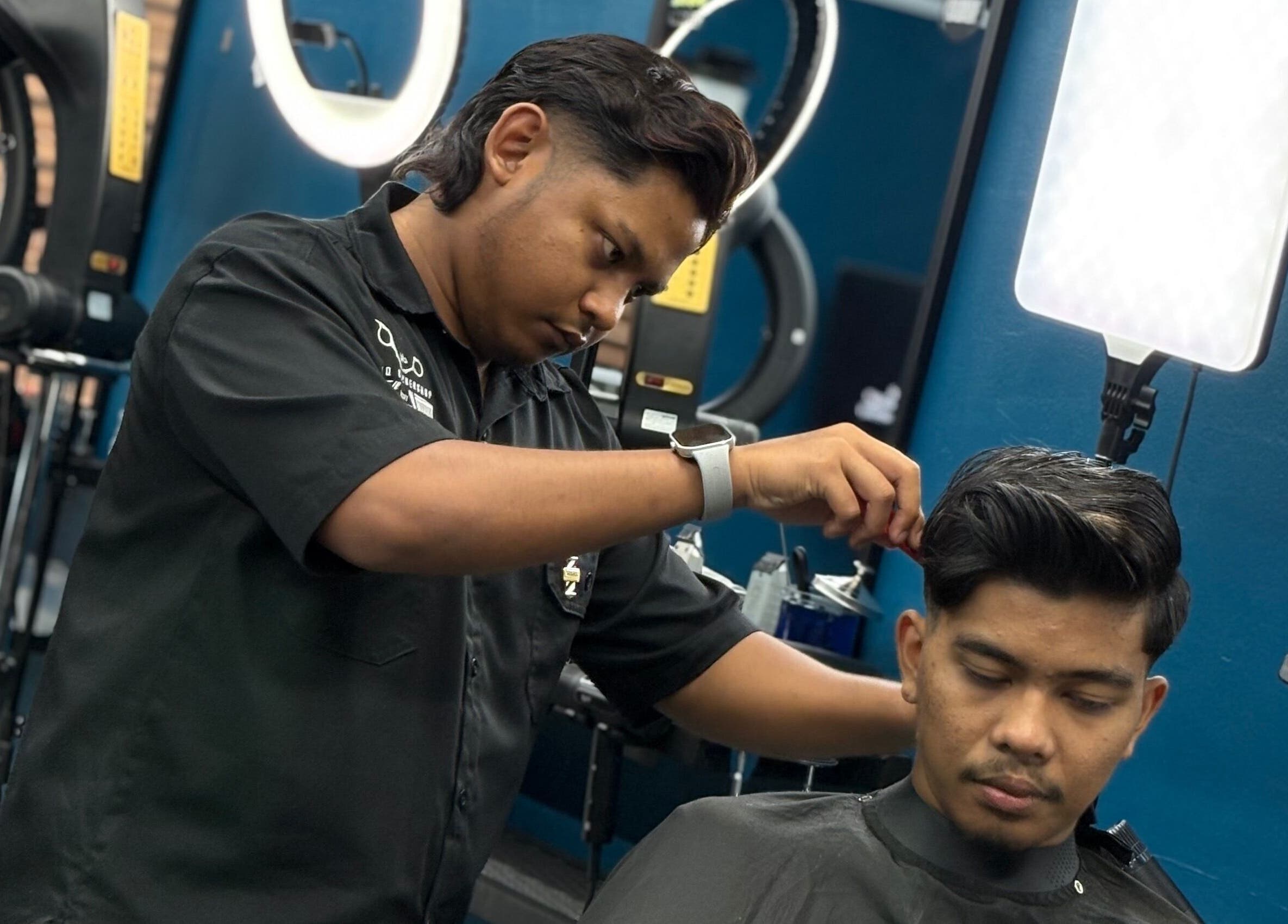 Barber expertly cuts hair at Daqiq Barbershop in Simpang Empat, Kedah, MY, showcasing precision and style.