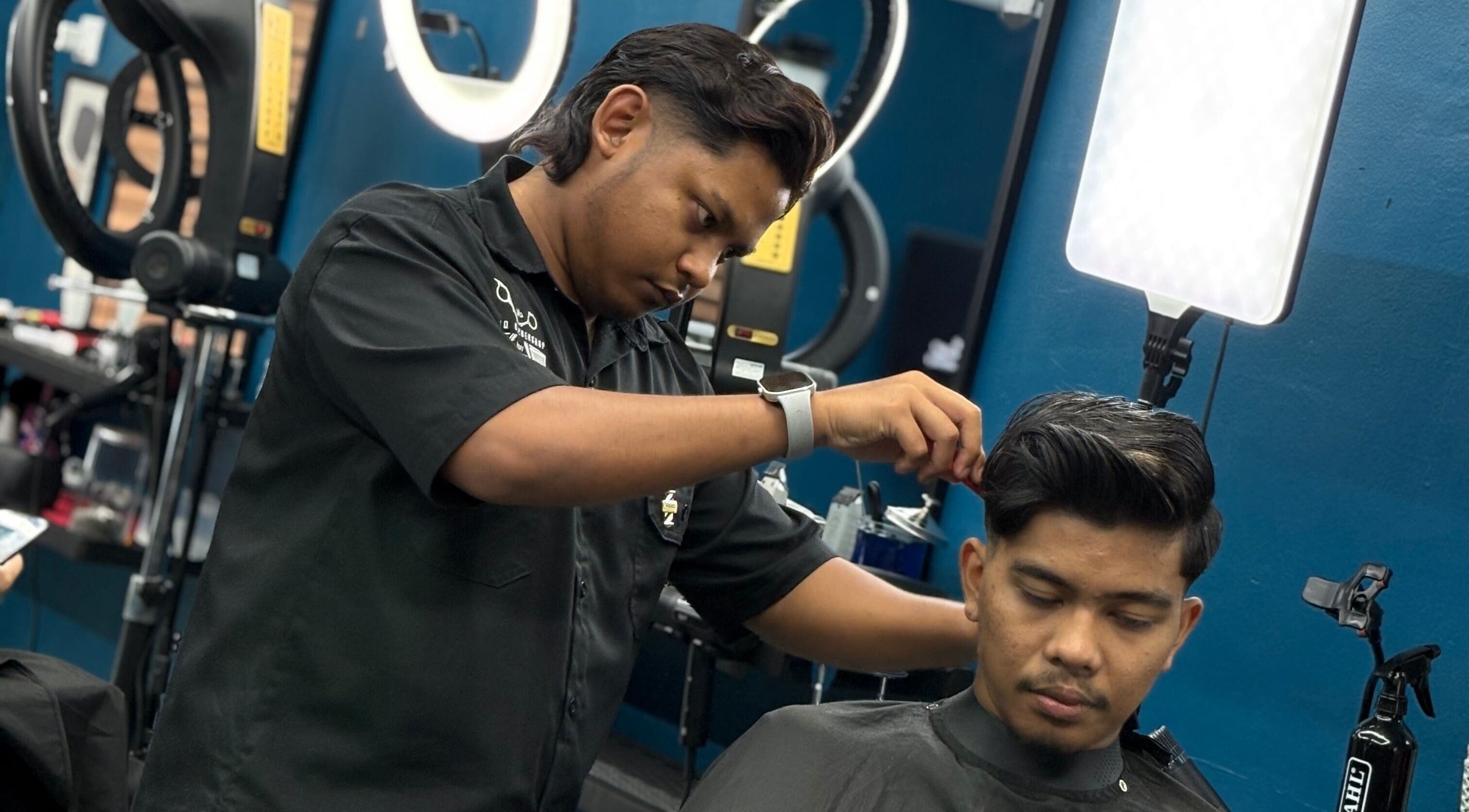 Barber expertly cuts hair at Daqiq Barbershop in Simpang Empat, Kedah, MY, showcasing precision and style.