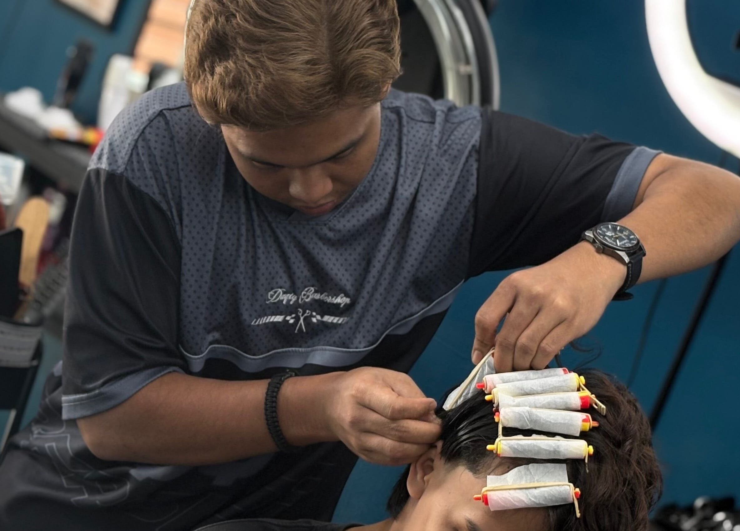 Barber giving a perm at Daqiq Barbershop, Simpang Empat, Kedah, MY, showcasing professional styling.
