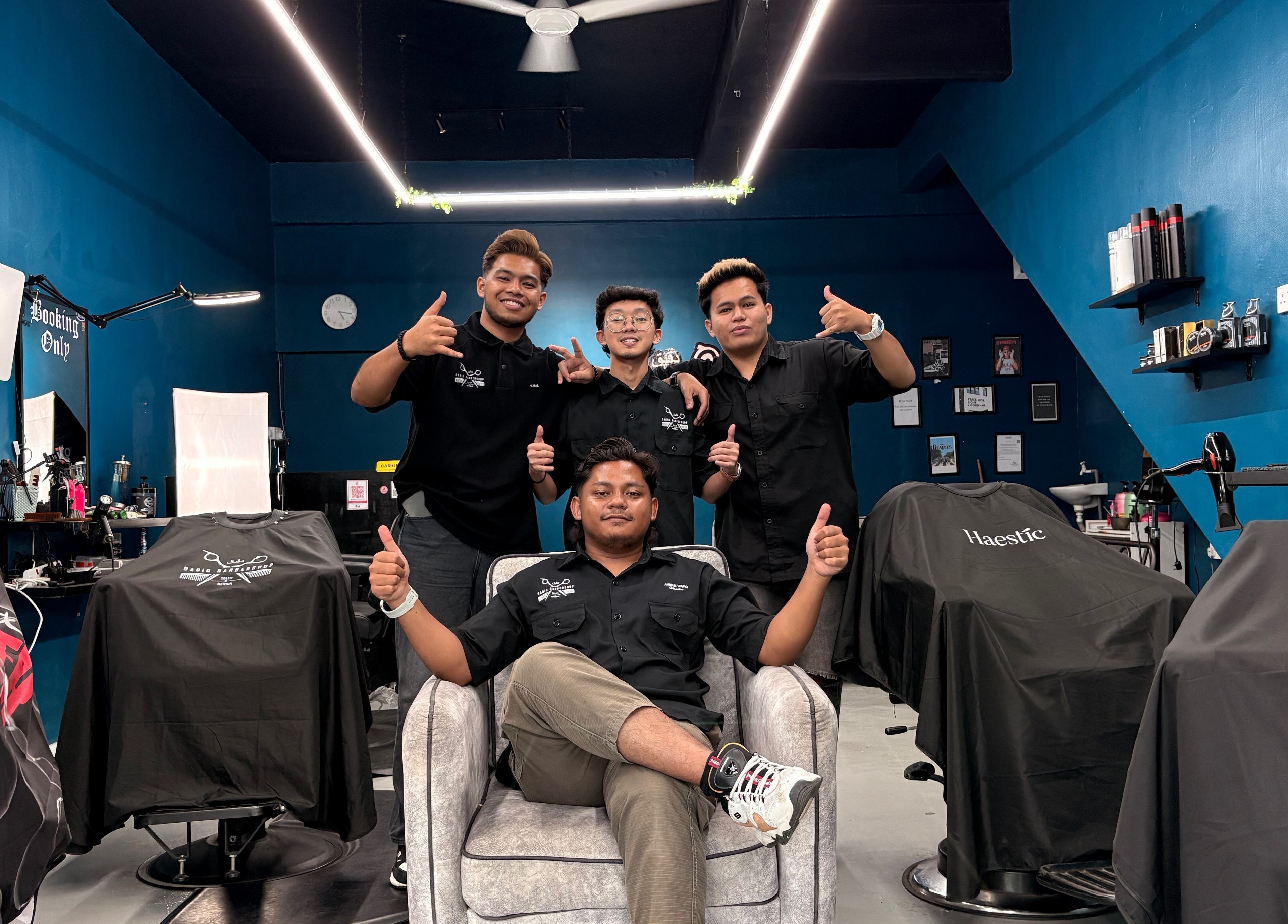 Friendly team at Daqiq Barbershop, Simpang Empat, Kedah, MY in a stylish, modern interior with chairs and mirrors.