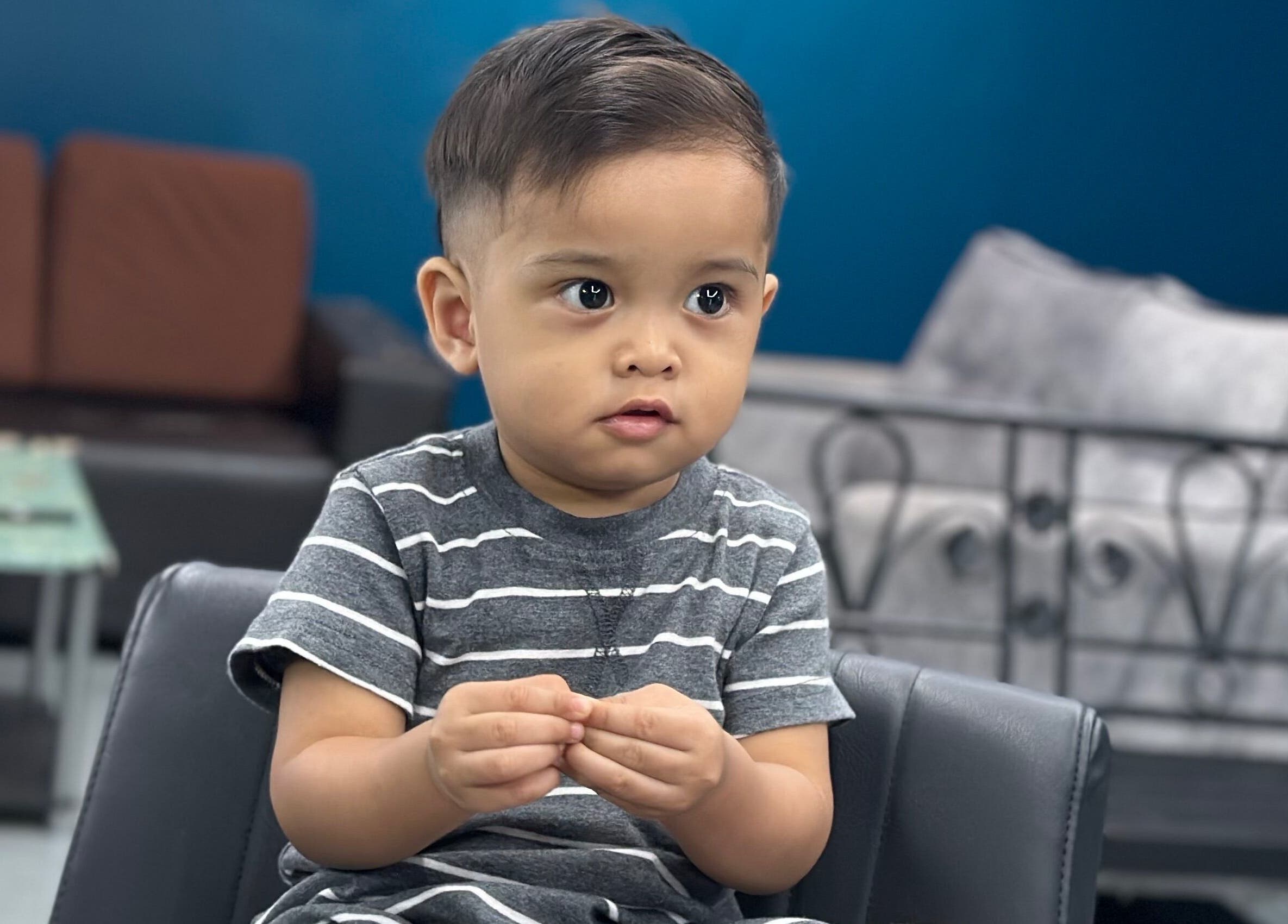 Young boy with neat haircut at Daqiq Barbershop, Simpang Empat, Kedah, MY, sitting on a salon chair.