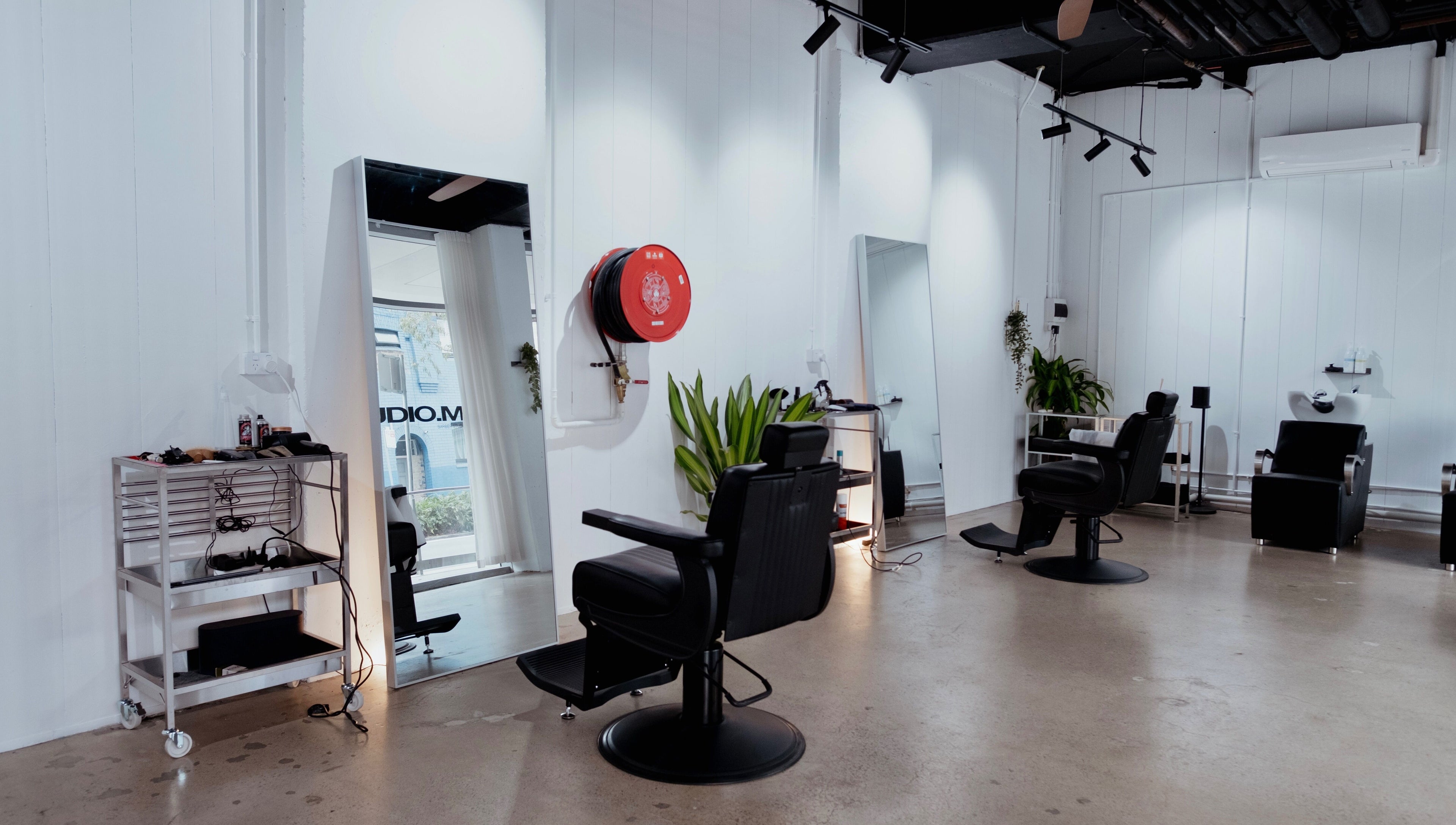 Modern interior of STUDIO.M in Camperdown, New South Wales, AU with sleek chairs, mirrors, and greenery.