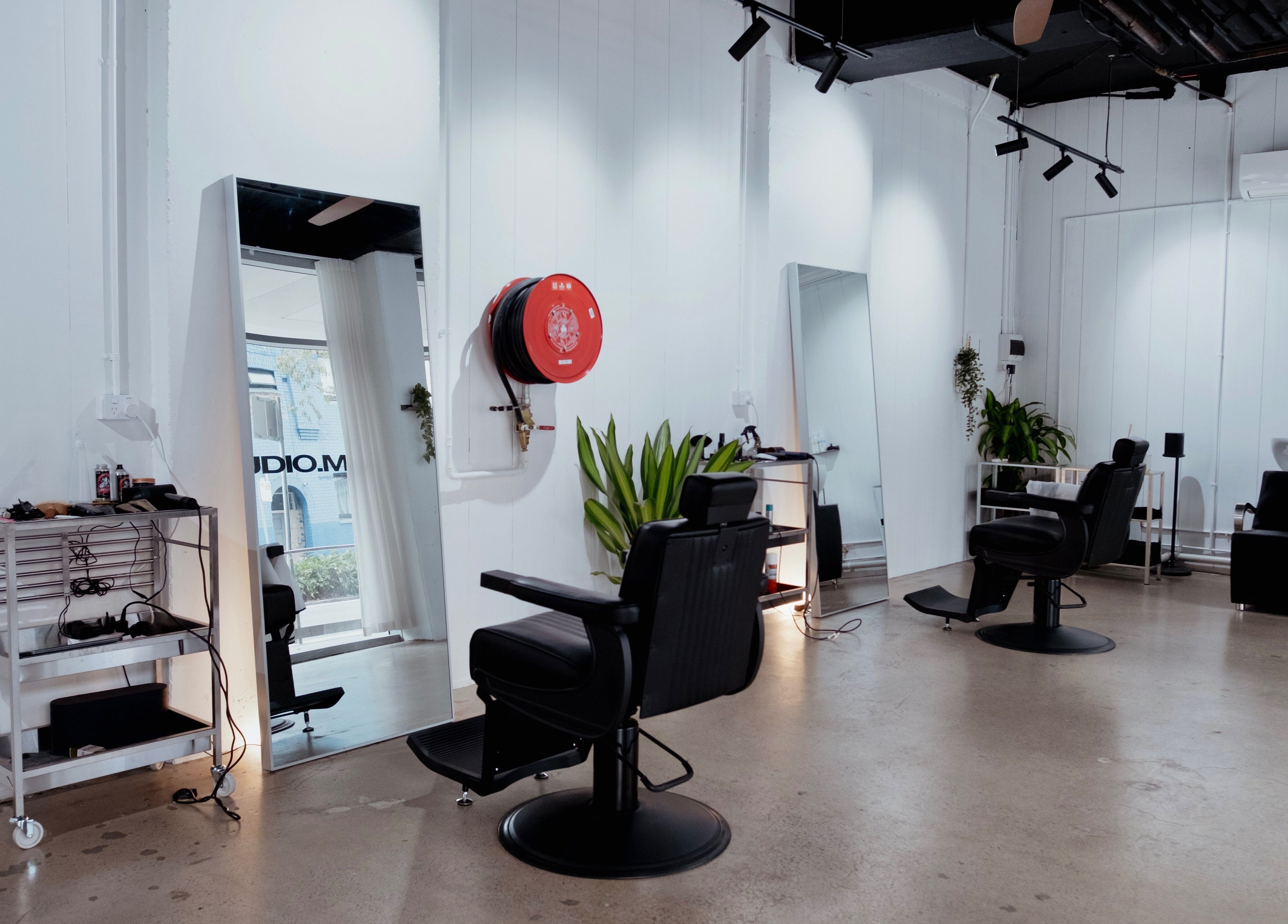 Modern interior of STUDIO.M in Camperdown, New South Wales, AU with sleek chairs, mirrors, and greenery.