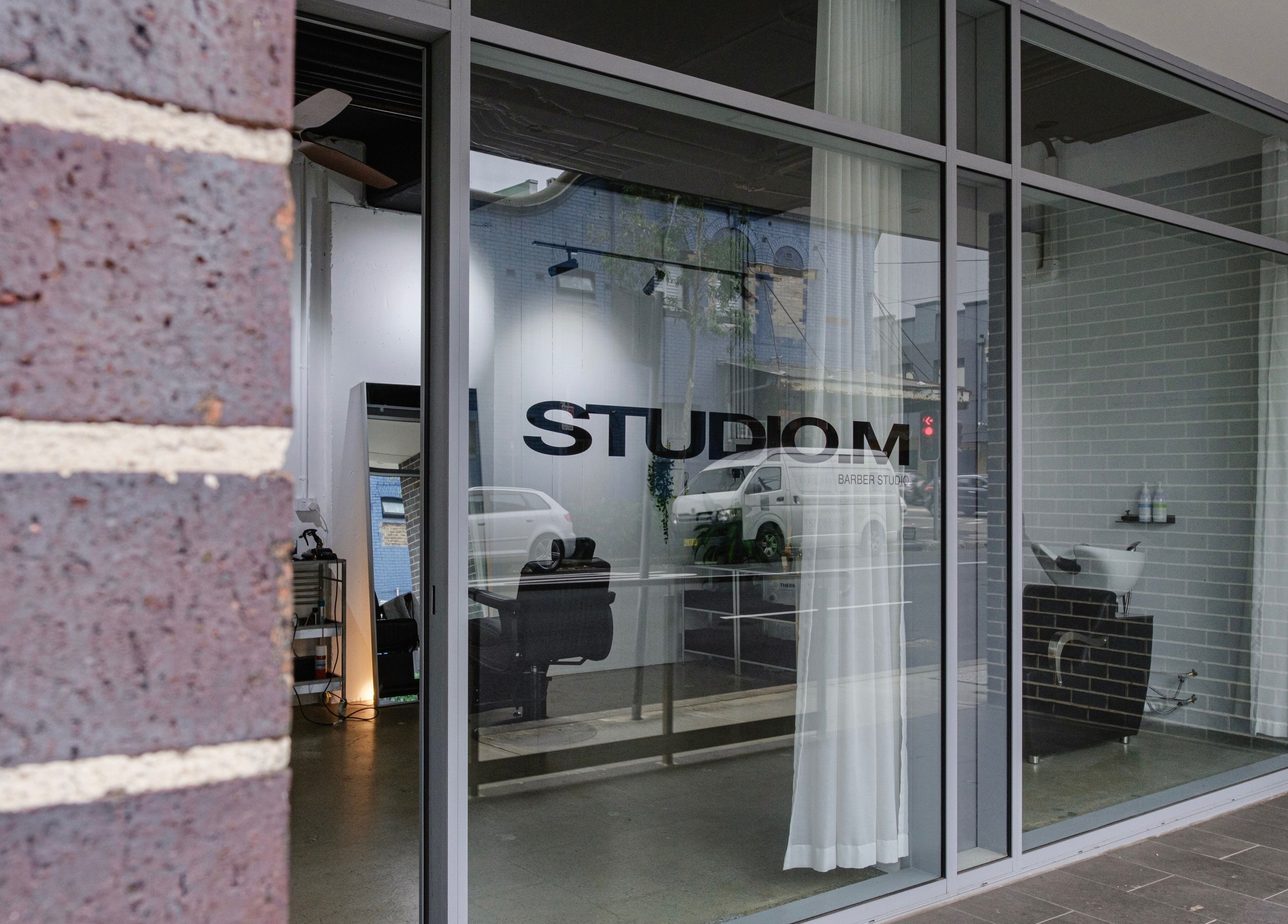 Exterior of STUDIO.M beauty salon in Camperdown, New South Wales, AU showcasing sleek glass facade.