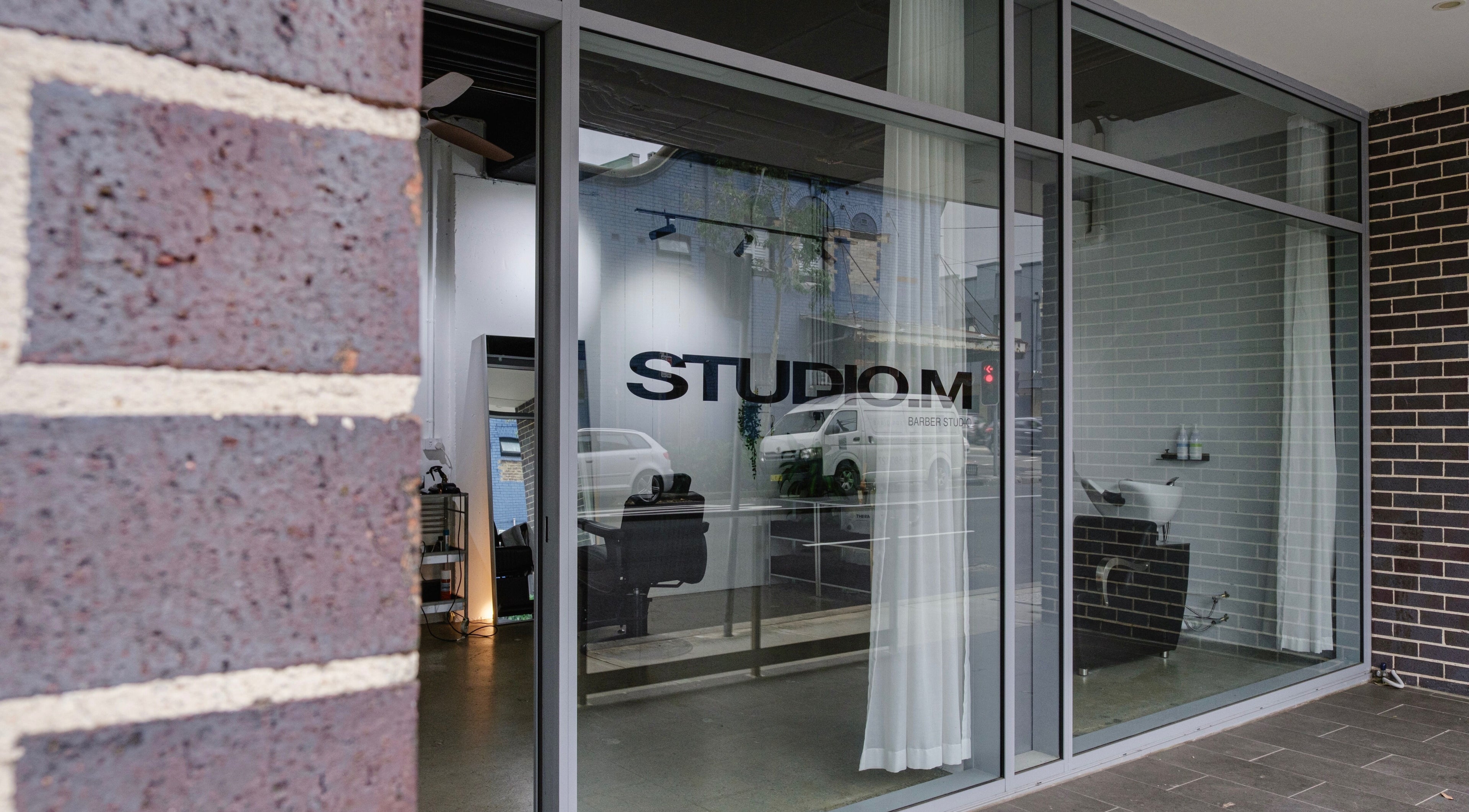 Exterior of STUDIO.M beauty salon in Camperdown, New South Wales, AU showcasing sleek glass facade.
