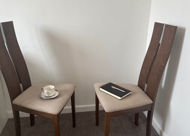 Cozy corner at Naomi Beckl IAPC&M Goal Setting Life Coach, Nottingham, England, GB with two chairs, a notebook, and a cup.