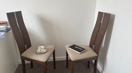 Cozy corner at Naomi Beckl IAPC&M Goal Setting Life Coach, Nottingham, England, GB with two chairs, a notebook, and a cup.