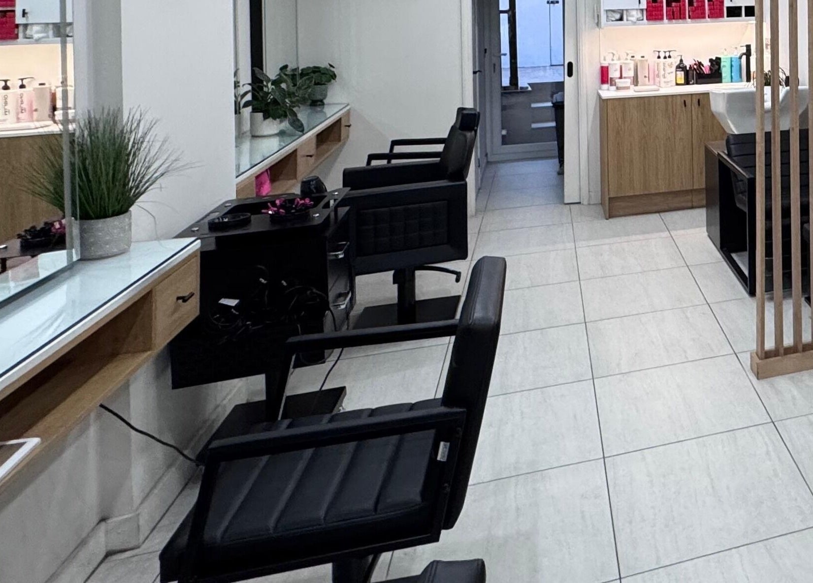 Modern interior of Rem and Nes salon in London, England, GB with sleek black chairs and beauty products.