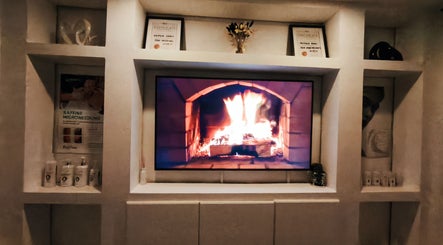 Inviting fireplace at Lunaria Aesthetics, Nazeing, England, GB, surrounded by elegant decor and certificates.