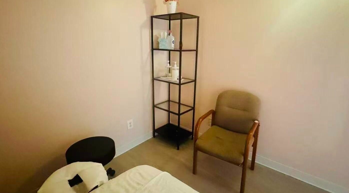 Cozy massage room at Massage Pro, Virginia, featuring a plush chair and organized shelf.