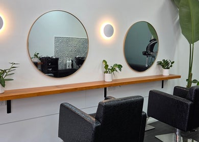 Elegant mirror setup at Papillon salon, Hendra, Queensland, AU with black chairs and lush green plants.