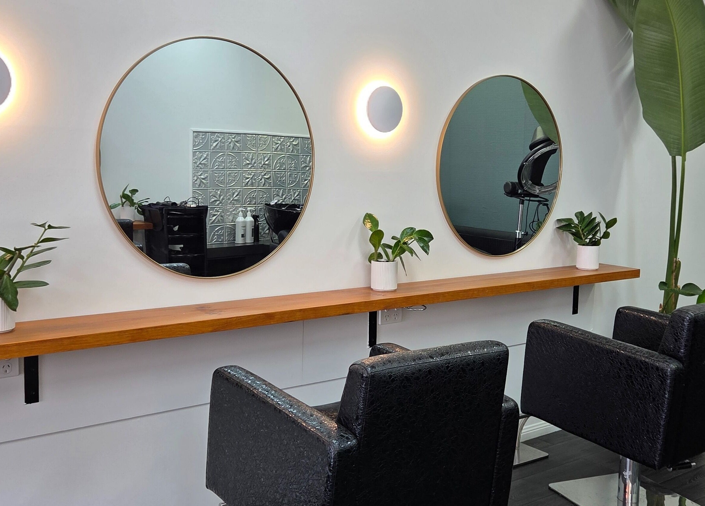 Modern salon chairs and round mirrors at Papillon salon, Hendra, Queensland, AU. Chic and inviting setting.