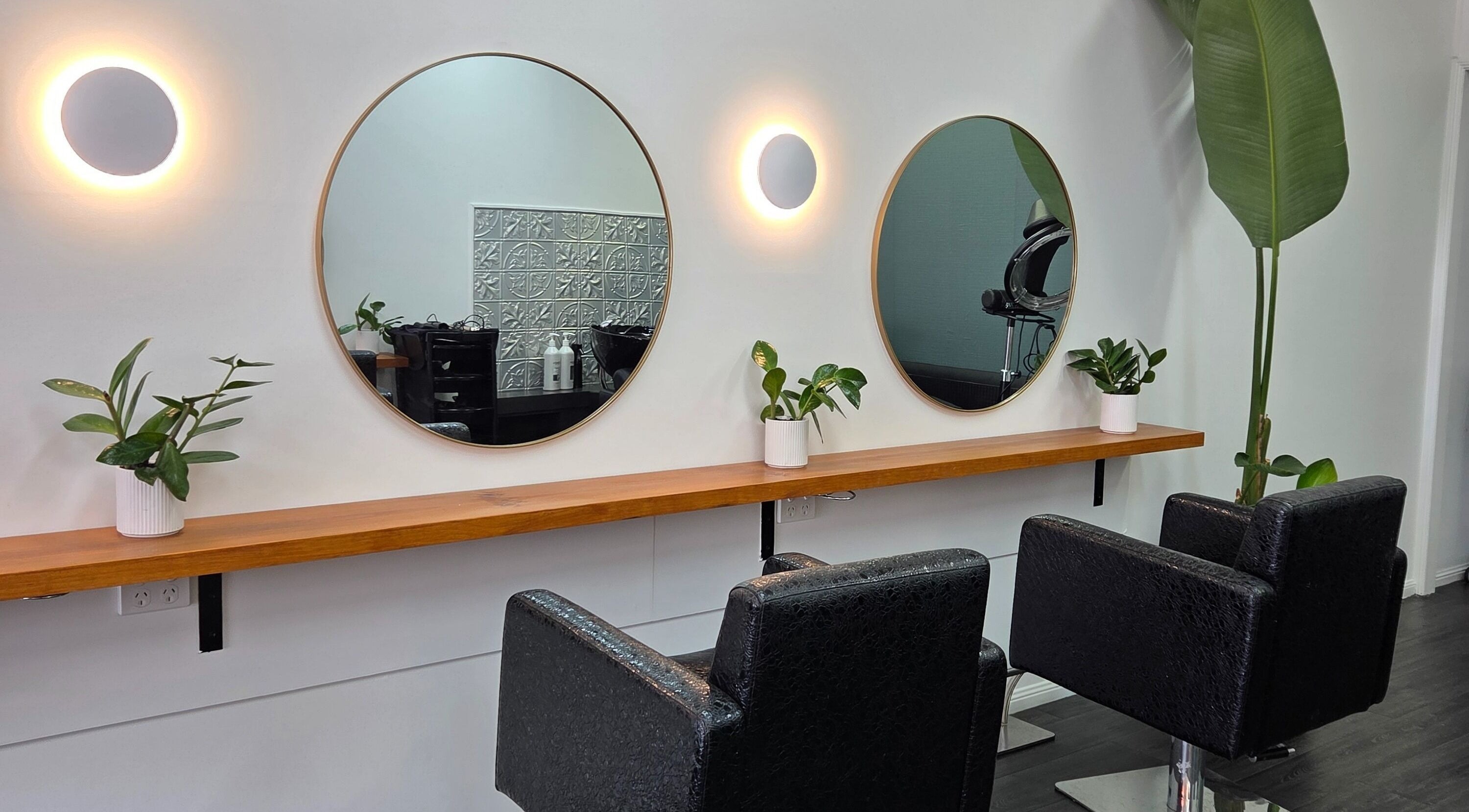 Modern salon chairs and round mirrors at Papillon salon, Hendra, Queensland, AU. Chic and inviting setting.