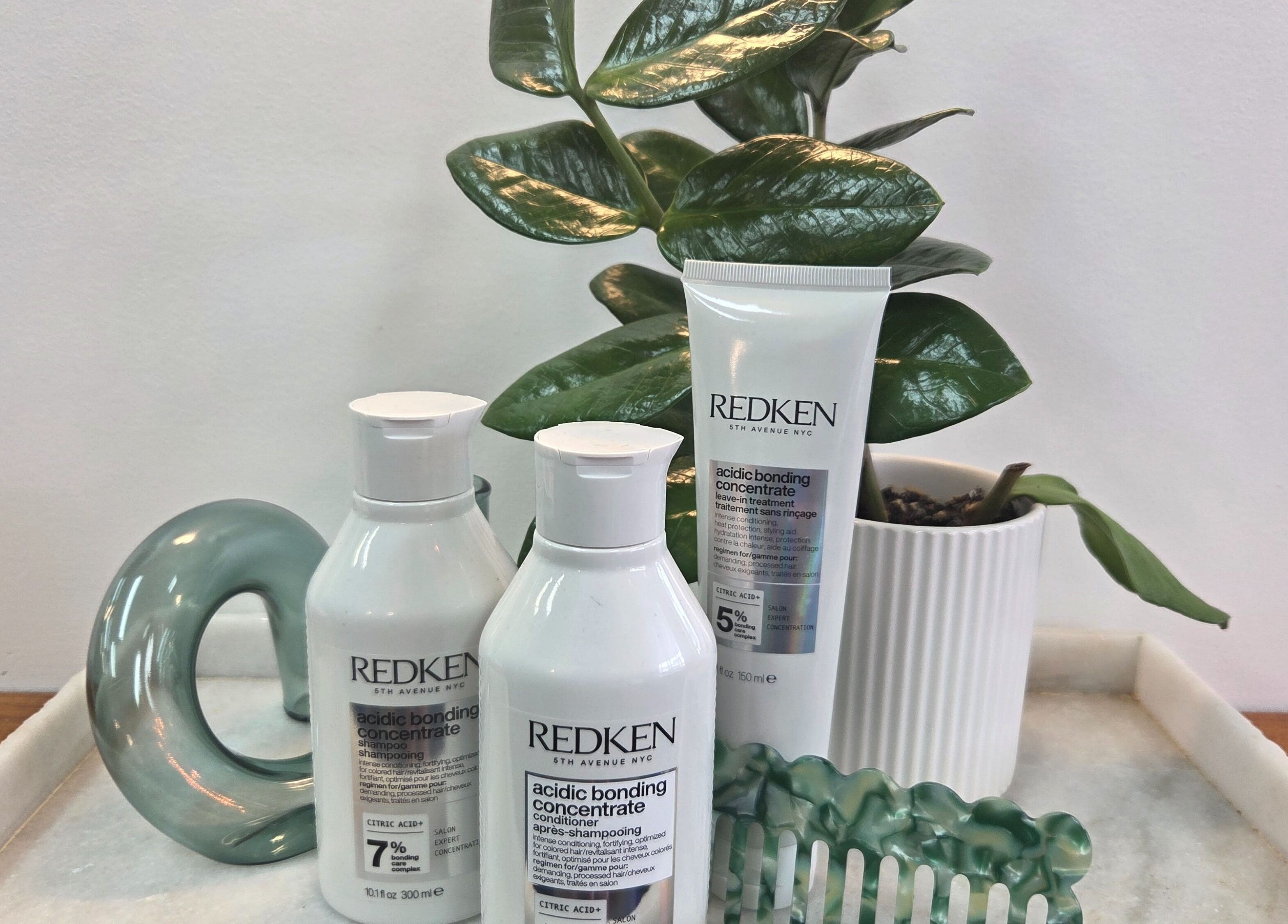 Redken haircare products on a tray at Papillon salon, Hendra, Queensland, AU, with lush plant decor.