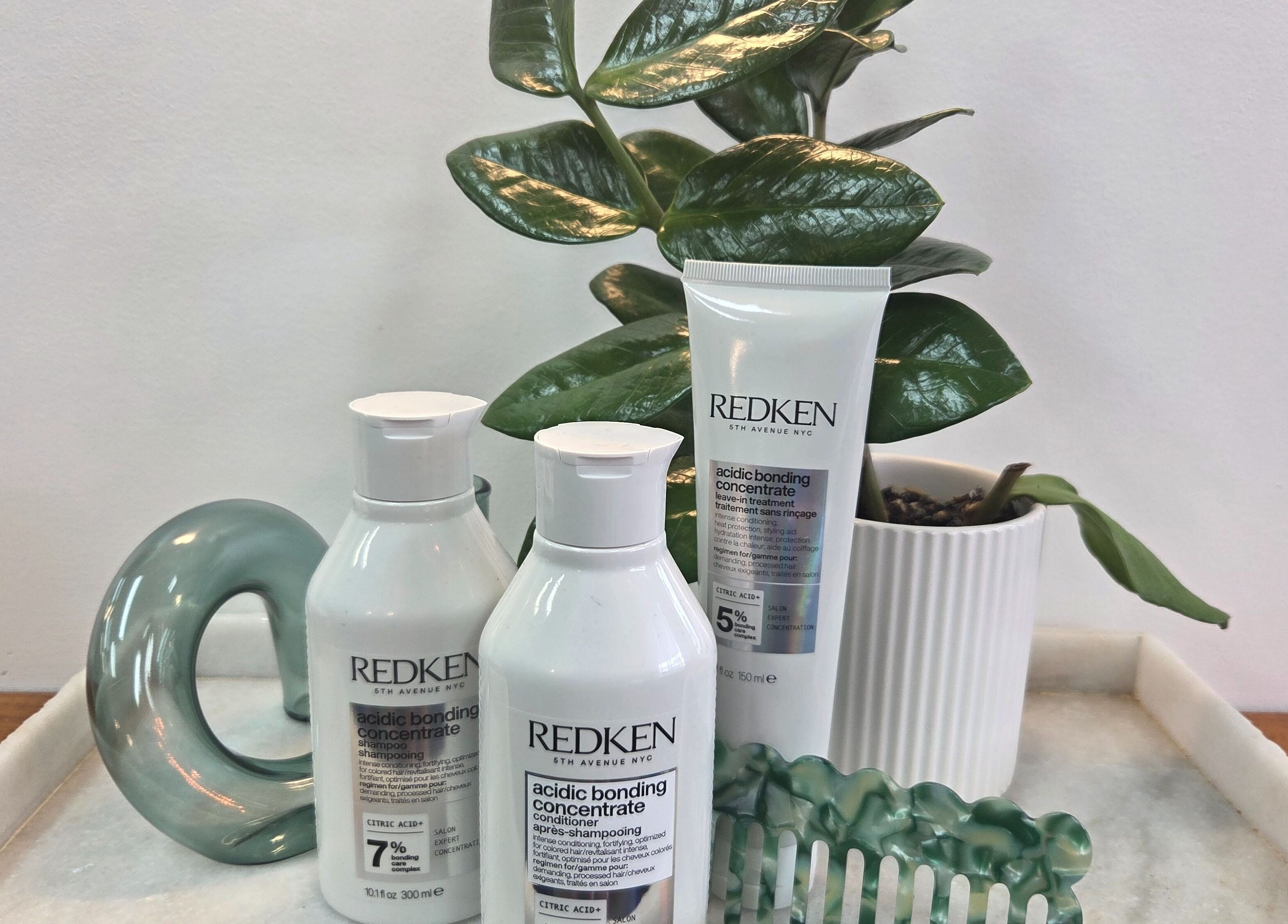 Redken haircare products on a tray at Papillon salon, Hendra, Queensland, AU, with lush plant decor.