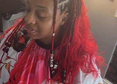 Colorful braids styled at Hair & Skin By Amber in Conyers, Georgia, US, showcasing vibrant red hues.