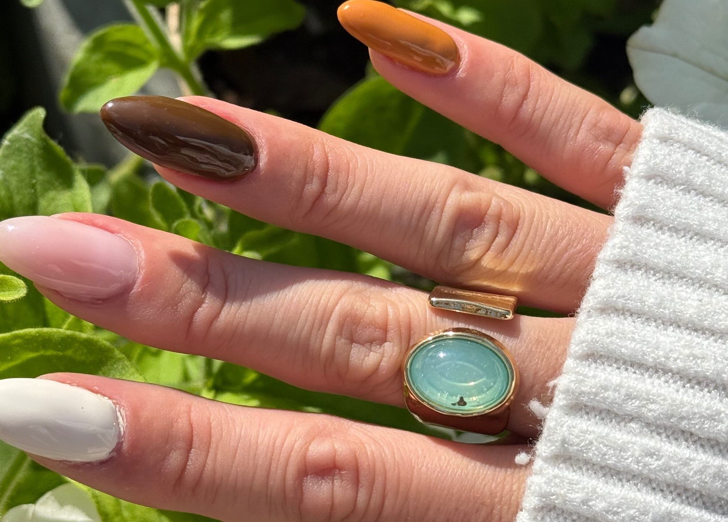 Elegant manicure at Popsie Nails in Newquay, England, GB featuring varied nail colors and stylish ring.