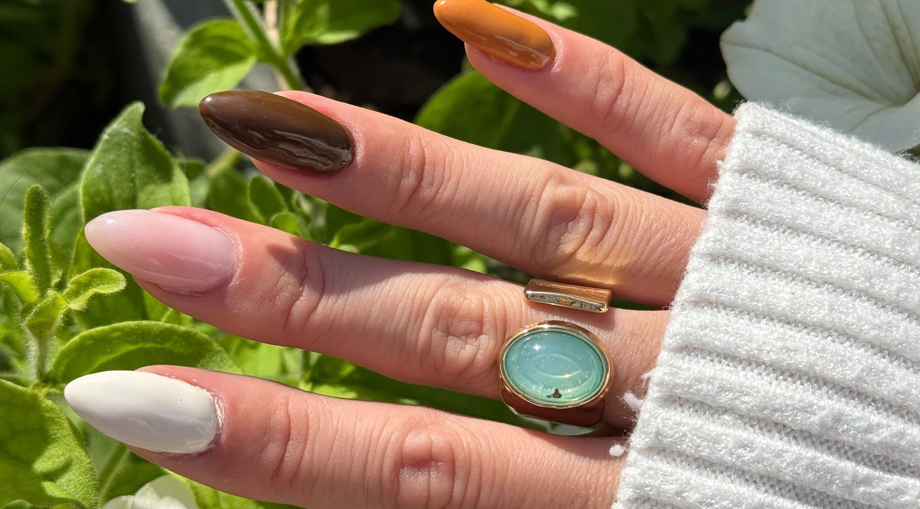 Elegant manicure at Popsie Nails in Newquay, England, GB featuring varied nail colors and stylish ring.